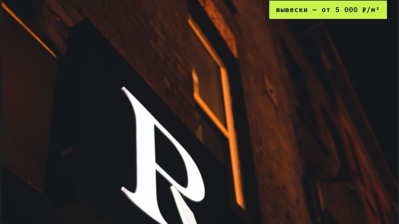 A facade sign at night with a per-square-meter price chip